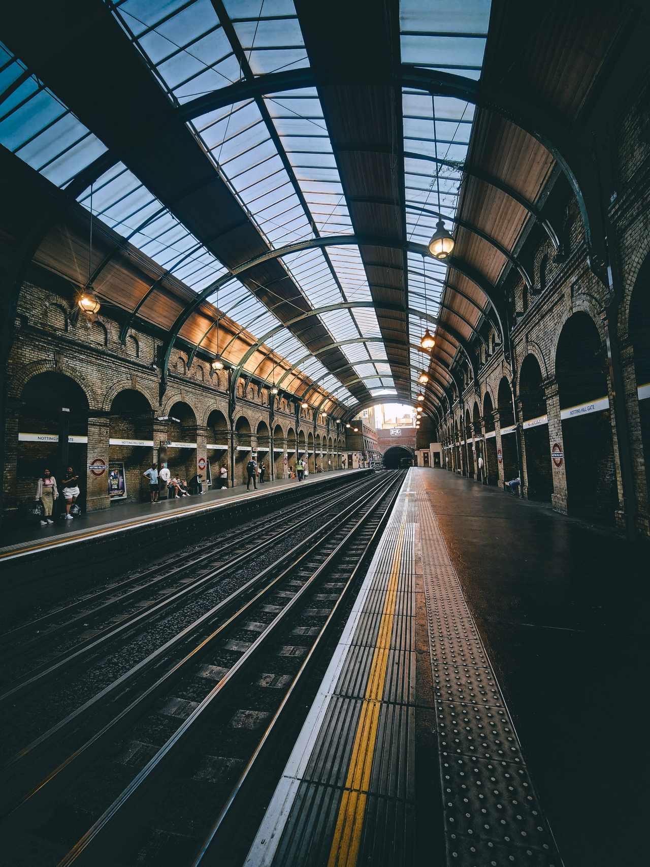 Platform at Notting Hill Gate under a glass roof on iron arches, with the track to the right